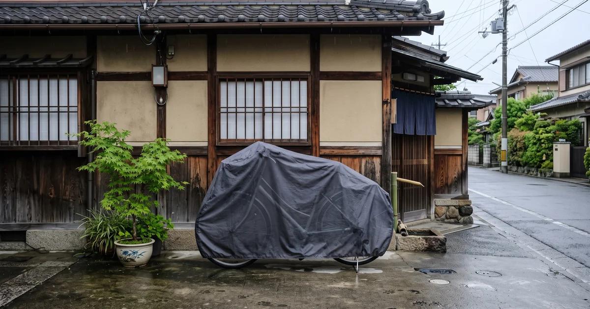 雨上がりの家の前で、グレーの自転車カバーを掛けて止めた自転車