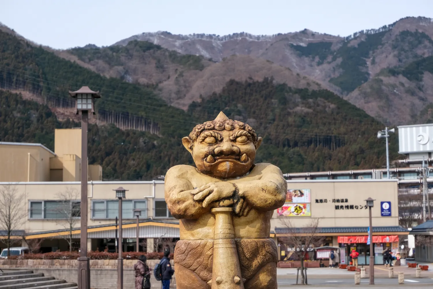 鬼怒川温泉駅前の鬼（鬼怒太）像と山々