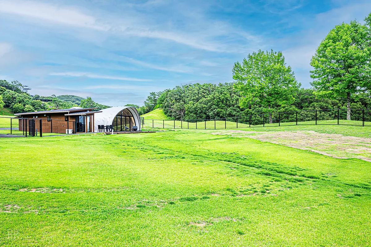 志摩グリーンアドベンチャー GLAMPING FIELD の客室と芝生の庭